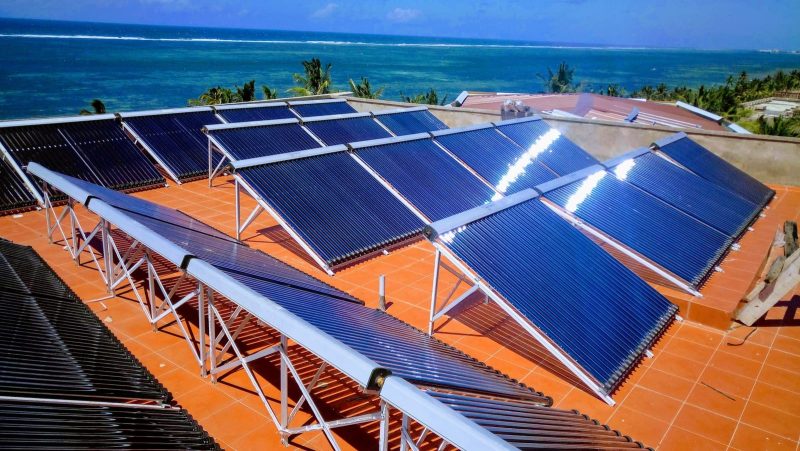 Centralized commercial solar water heater with rows of vacuum tube collectors on a seaside roof